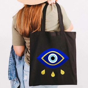 Black canvas tote bag featuring a Greek Evil Eye graffiti print and golden teardrop accents
