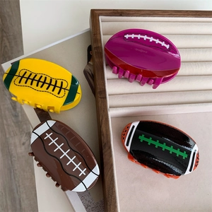 Détail de pinces à cheveux en acrylique forme rugby en jaune, violet, marron et noir