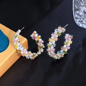 Macro shot of silver C-hoop earrings featuring colorful rectangular cubic zirconia stones