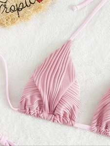 Dettaglio del top bikini rosa a costine con lacci allacciati al collo su sfondo bianco