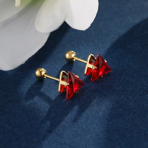 Macro shot of triangle cut red gems set in gold stainless steel with screw ball backs