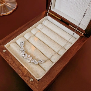 Silver wheat-ear necklace with clear zircons showcased in a wooden jewelry box