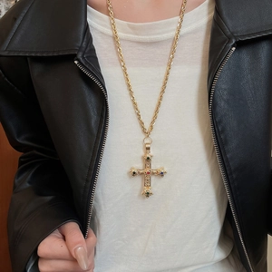 Detailed view of a vintage baroque cross necklace with colorful gems on a thick gold chain