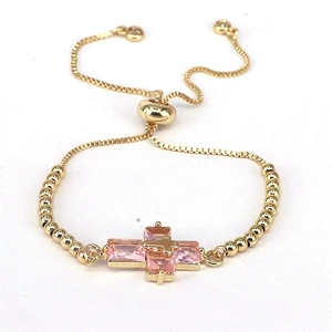 Adjustable golden bead bracelet featuring a pink cubic zirconia cross pendant on white back