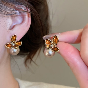 Detailed macro view of amber flower petal earrings with a large champagne pearl droplet