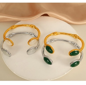 Detail of gold and silver open bangles with green and white oval cat eye stones