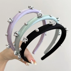 Close-up of three knotted velvet headbands with silver metal studs in purple blue and black