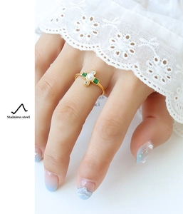 Detailed view of a gold stainless steel ring with pearl and green zircon on a model