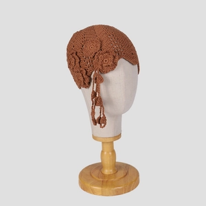 Detail of brown handmade crochet beanie featuring floral applique and retro tassels