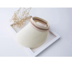 Dettaglio della visiera in paglia color crema con fascia elastica a righe e trama