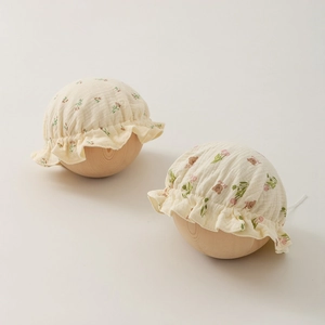 Detail of newborn baby caps featuring floral and bear prints on breathable cotton gauze fabric