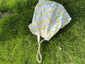 Detail of floral and blue checkered pattern on cotton tote bag over a green lawn