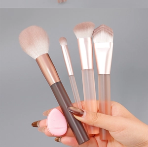 Detail of 4 travel makeup brushes and a pink beauty blender with frosted resin handles