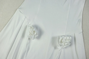 Close-up of white dress fabric with elegant 3D handcrafted fabric rose decorations