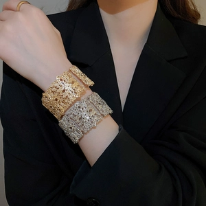 Gros plan détaillé de bracelets larges évidés dorés et argentés avec motif floral
