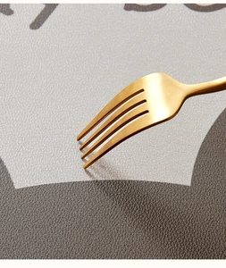 Macro detail of faux leather bathroom mat showing gray and brown texture with a gold fork