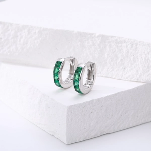 Détail des boucles d'oreilles en argent S925 avec zircons verts sur marbre blanc