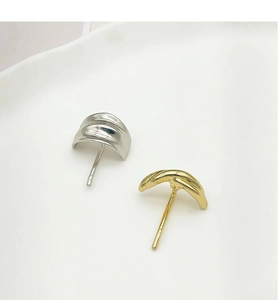 Close-up of minimalist gold and silver textured metal hair hooks on a white ceramic plate