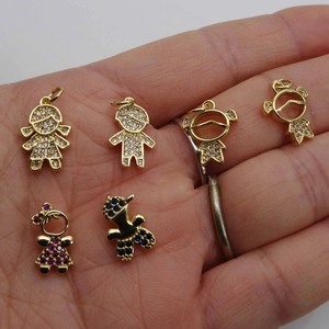 Cute boy and girl charms with micro-paved zircons held on hand for size perspective
