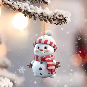 Close-up of a cute snowman ornament hanging from a snowy pine branch with warm bokeh