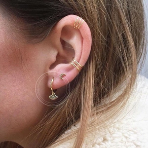 Gold layered earring set with sun, moon, and devil eye charms shown on a model ear