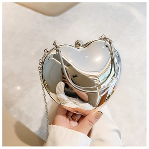 Close-up of heart-shaped silver mirror evening bag with metal handle and chain