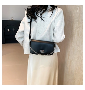 Black flap crossbody bag with silver chain strap and metal ring lock shown on model