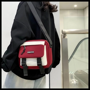 Outdoor shot of red and cream canvas crossbody bag with PINBO BAG logo and adjustable strap