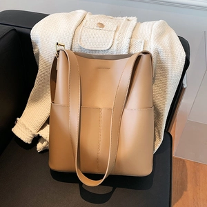 Detailansicht der khakifarbenen Leder-Eimertasche auf schwarzem Sofa mit Fronttasche