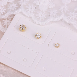Detailed macro of three gold star stud earrings with clear zircon on a white display card