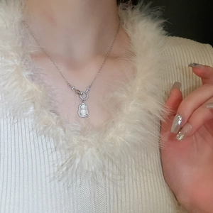 Close-up of silver gourd necklace with white gemstone on model wearing a white fur coat