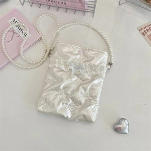 Dettaglio della mini borsa in raso bianco con ricamo a fiocco e tracolla di perle