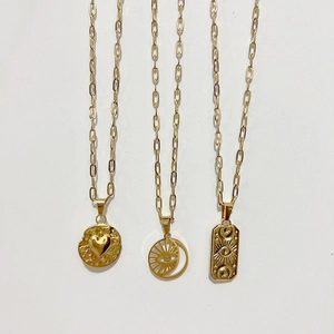 Bohemian style gold paperclip necklaces with heart and celestial eye charms on white background
