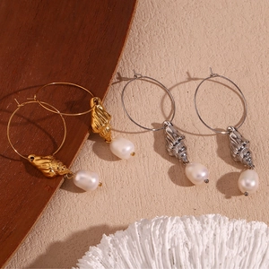 Close-up of gold and silver conch shell hoop earrings with drop-shaped pearls