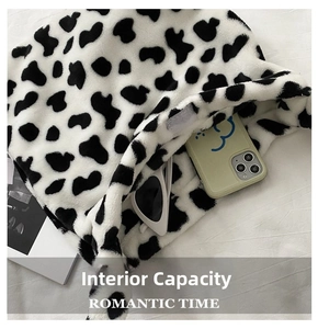 Detail view of the large capacity interior of cow print plush shoulder bag with accessories
