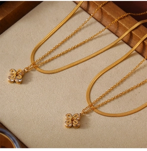 Close-up of golden clover pendant with zircon inlay on a double-layer snake chain necklace