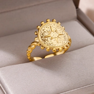 Close-up of gold plated stainless steel ring with textured oval face and twisted band