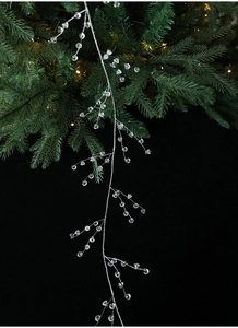 Detail of silver Christmas crystal bead garland hanging on a green pine tree branch