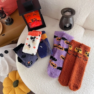 Flat lay of colorful plush Halloween crew socks with pumpkin and ghost motifs on soft fur