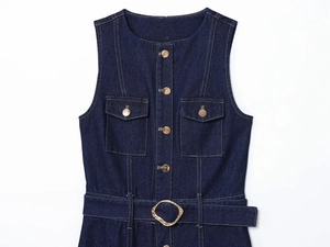 Detail of dark blue denim dress showing gold buttons and belt buckle on white background
