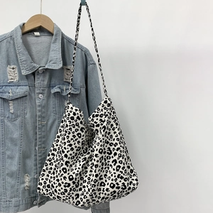 Close-up of leopard print corduroy tote bag hanging on a light blue denim jacket