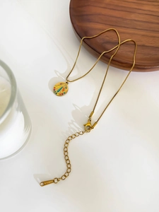 Macro shot of gold stainless steel necklace featuring colorful enamel fan-shaped pendant