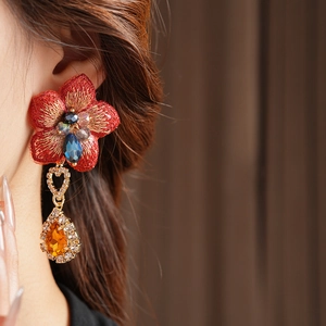Détail de boucle d'oreille fleurie vintage avec broderie rouge et pierre ambre goutte