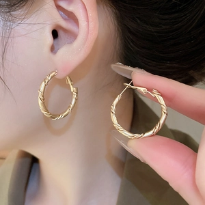 Detailed close-up of matte gold twisted rope hoop earrings showing textured metal finish