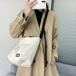 Close-up of white canvas messenger bag with adjustable strap and fashion label detail