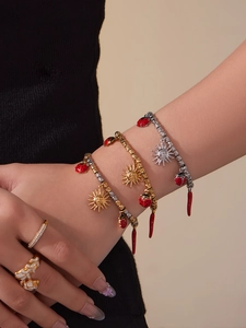 Close-up of layered gold charm bracelets with red ladybug and sun pendants on model