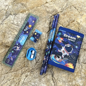 Space-themed kids stationery set with pencils, ruler, eraser, and wallet on a rock surface