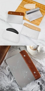 Macro view of stainless steel dough scrapers with wooden handles and inch scale markings