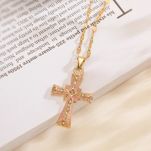 Vintage 18K gold plated cross necklace with pink enamel and sparkling zircons on a book