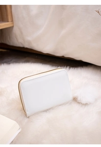 Close-up of white faux leather zipper purse with a fluffy pom-pom charm detail